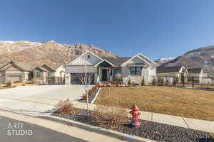 View of front of home with stone siding, a mountain view, driveway, and a garage