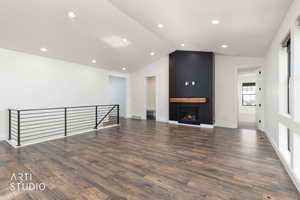 Unfurnished living room with lofted ceiling, a fireplace, dark wood-style floors, and recessed lighting