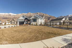 View of front of house with stone siding, a mountain view, a porch, concrete driveway, and an attached garage