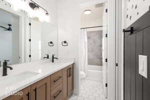 Bathroom with double vanity, shower / tub combo, and light tile patterned flooring