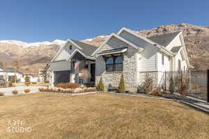 View of front facade with a mountain view, stone siding, and a garage