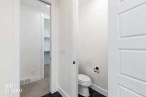 Bathroom with dark tile patterned floors, a walk in closet, and dark colored carpet