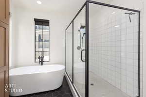 Bathroom featuring a stall shower, a freestanding bath, and dark tile patterned flooring