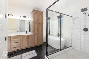 Full bathroom with a stall shower, a freestanding bath, vanity, and dark tile patterned floors
