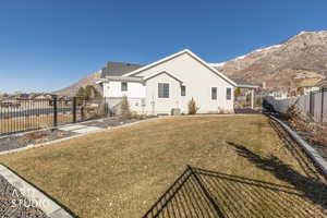 Back of house with a mountain view and a fenced backyard