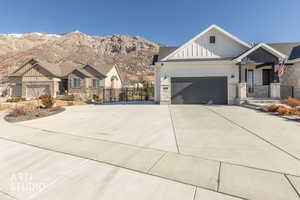 View of front facade featuring board and batten siding, stone siding, concrete driveway, an attached garage, and a mountain view