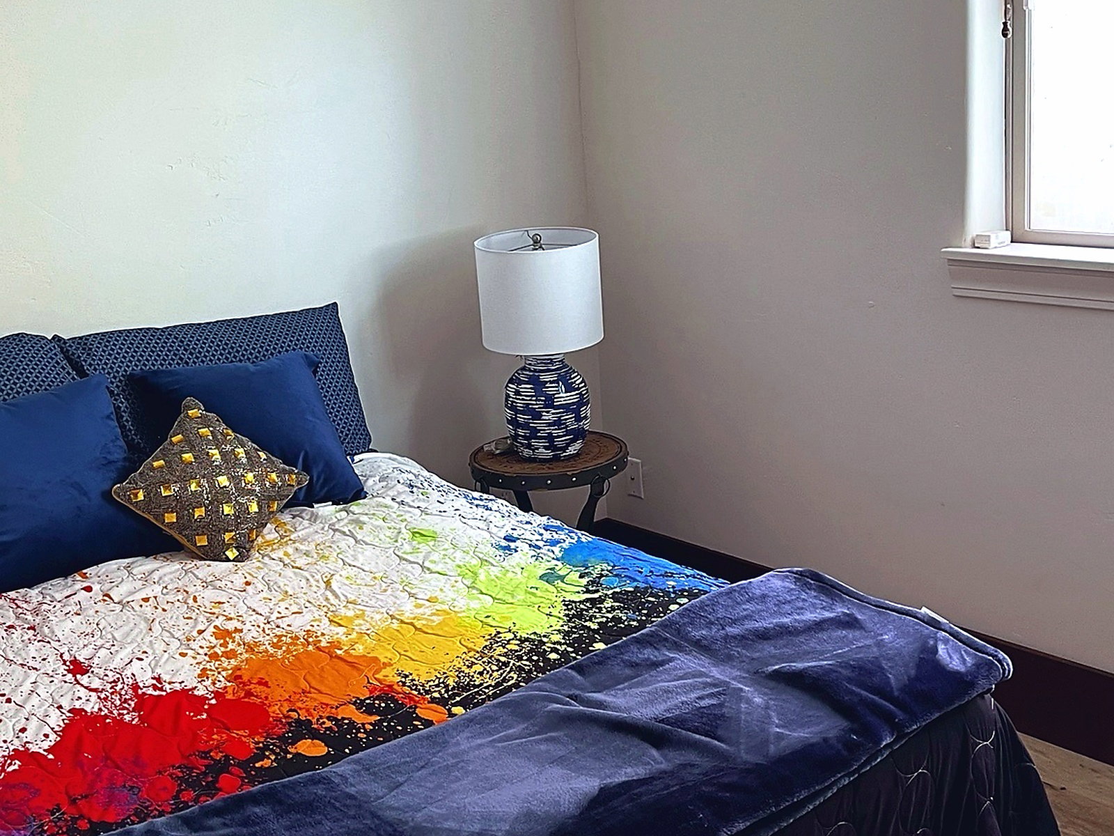 Bedroom featuring a window with white trim, light-toned walls, and a dark baseboard