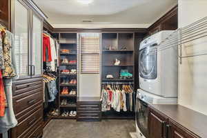 Primary suite showcasing a massive walk-in closet with the added convenience of a private stackable washer and dryer.