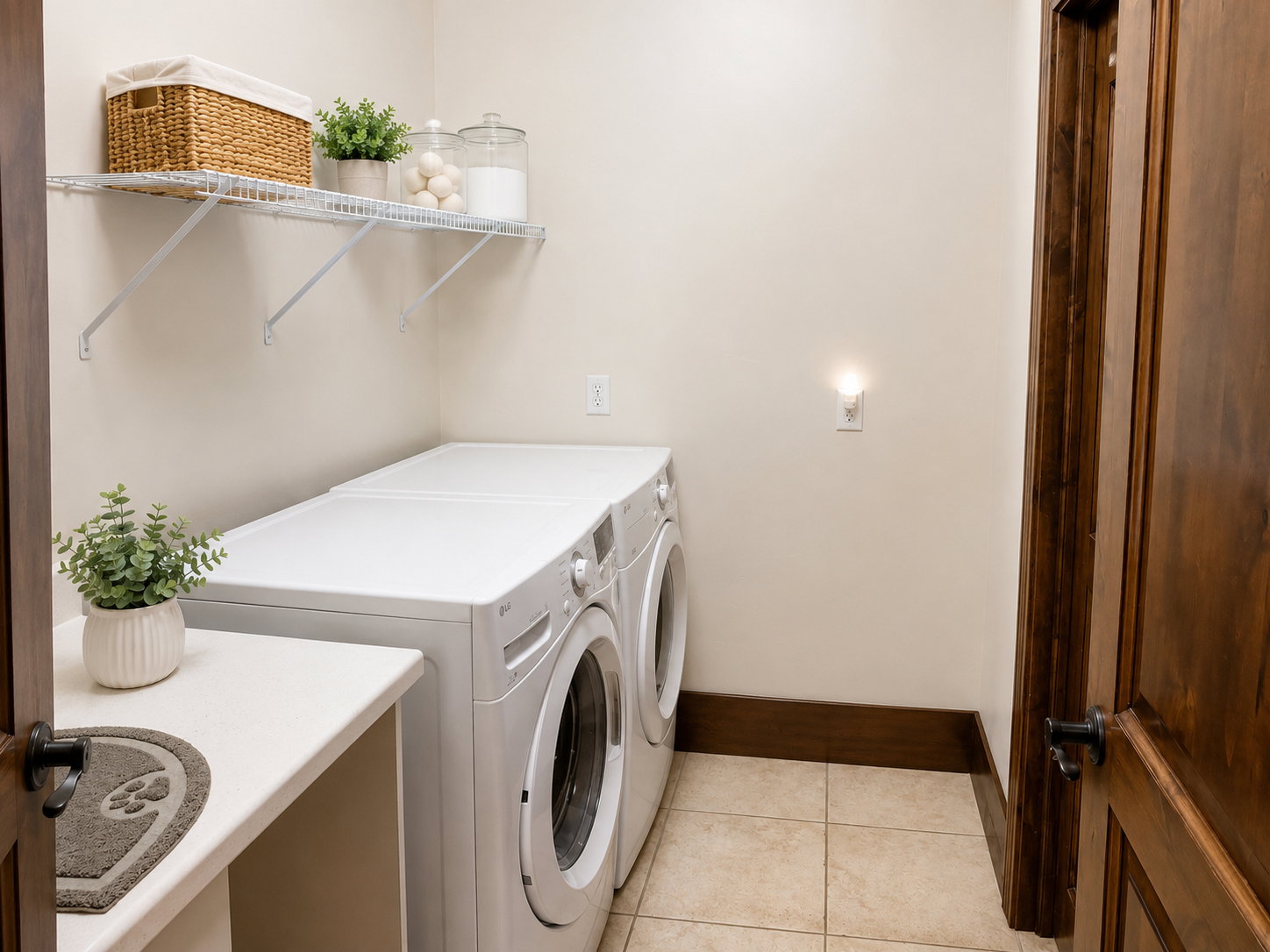 Dedicated laundry area featuring a built-in countertop, upper wire shelving, and neutral tile flooring