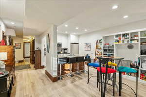 Kitchen with white cabinets, a breakfast bar area, light wood-type flooring, appliances with stainless steel finishes, and recessed lighting