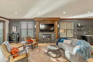 Living area with ornamental molding, wood finished floors, a large fireplace, and recessed lighting