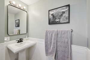 Half bathroom featuring wainscoting and a decorative wall