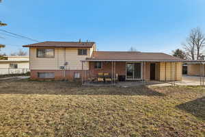 Rear view of property with brick siding, a lawn, a patio, and a shingled roof