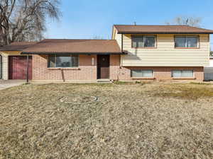 Split level home with concrete driveway, brick siding, a garage, and a shingled roof