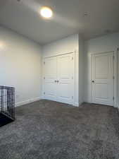 Unfurnished bedroom with dark carpet and a closet