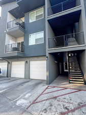 Rear view of house with stucco siding, an attached garage, driveway, and a balcony