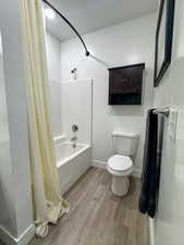 Full bath featuring shower / tub combo, light wood finished floors, and a textured ceiling