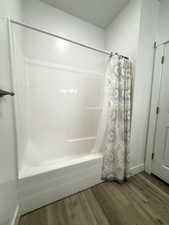 Full bathroom featuring shower / bath combo with shower curtain and dark wood finished floors