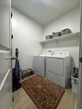 Laundry area with light wood finished floors and independent washer and dryer
