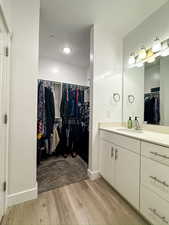 Bathroom featuring a spacious closet, vanity, a textured ceiling, and light wood-style flooring