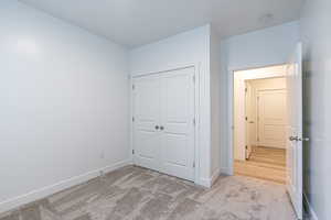Unfurnished bedroom featuring light colored carpet and a closet