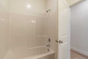 Bathroom featuring washtub / shower combination and light wood-style floors