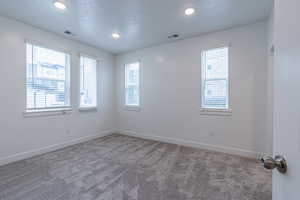 Carpeted spare room featuring a textured ceiling and recessed lighting