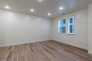 Room with a textured ceiling, light wood-type flooring, and recessed lighting