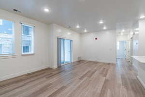 Empty room with light wood finished floors, recessed lighting, and a textured ceiling
