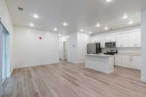 Kitchen with a center island with sink, white cabinetry, light wood-style floors, stainless steel appliances, and recessed lighting