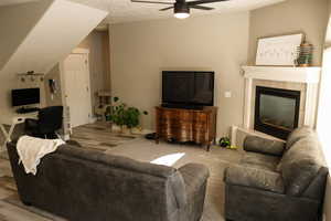 Living room with wood finished floors, a desk, a fireplace, and ceiling fan