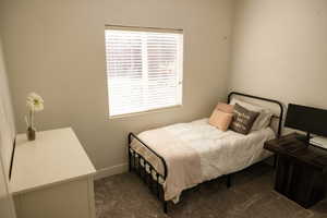 Bedroom with dark colored carpet and baseboards