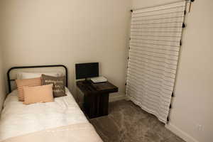 Bedroom featuring dark carpet and baseboards