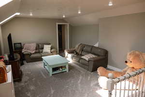Carpeted living room with lofted ceiling and recessed lighting