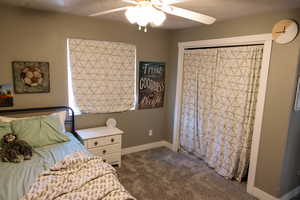 Bedroom with dark colored carpet and a ceiling fan
