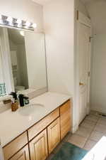 Bathroom with vanity, light tile patterned flooring, and lofted ceiling