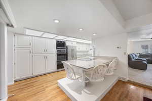 Kitchen with white cabinetry, a kitchen breakfast bar, light stone counters, black appliances, and a peninsula