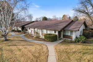 View of front of home with a front yard, a shingled roof, and brick siding