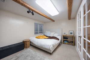 Carpeted bedroom with beam ceiling