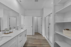Full bathroom featuring a stall shower, double vanity, and dark wood-type flooring