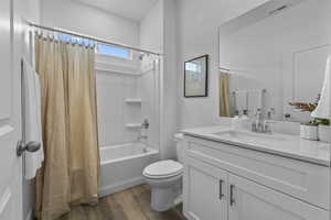 Bathroom featuring shower / bath combo with shower curtain, vanity, and dark wood-style floors