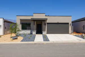 Contemporary house featuring concrete driveway, stucco siding, a garage, and stone siding