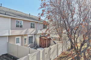 Back of property featuring a shed, a fenced backyard, a shingled roof, and a gate