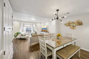 Dining space with dark wood-style flooring, a chandelier, a textured ceiling, and recessed lighting