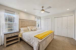 Carpeted bedroom with multiple closets, ceiling fan, and recessed lighting
