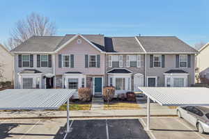 View of front facade featuring a shingled roof, uncovered parking, and stone siding