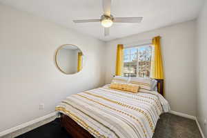 Carpeted bedroom featuring ceiling fan and baseboards