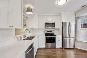 Kitchen with appliances with stainless steel finishes, white cabinets, dark wood-style floors, a textured ceiling, and light stone countertops