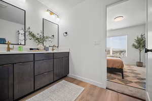 Bathroom with double vanity, ensuite bathroom, and light wood-style floors