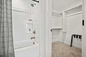 Bathroom with shower / tub combo, light colored carpet, and a spacious closet
